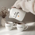 Zestaw biały porcelanowy dzbanek 1 litr i 2 kubki porcelanowe 300 ml - motyw złotego serca z napisami Na długie rozmowy oraz Do końca życia i jeden dzień dłużej dla pary na rocznicę ślubu 3P4A9133.webp