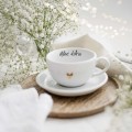 Biała filiżanka porcelanowa 250 ml ze spodkiem - motyw złotego serca z napisem Chłoń dobro dla bliskiej osoby na urodziny Zbliżenie na złote zdobienie serca na białym filiżance porcelanowej ze spodkiem - Chłoń dobro nadzwyczajnie.mom